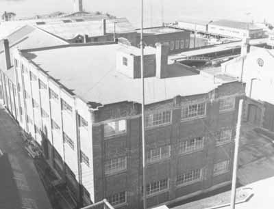 Exterior view of Oil Stores, Building 83, showing the scale, massing and well-propportioned, symmetrical composition of this large, three-storey, flat-roofed brick structure, 1989. (© (Ian Doull, AHB, Parks, 1989.))