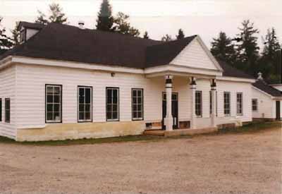 General view of the Main Hatchery Building, showing the low massing of the one-storey, wood structure with its symmetrical façade and hipped roof with gabled dormer windows, 1993. © Parks Canada Agency / Agence Parcs Canada, 1993.