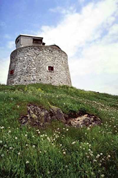 General view of the Carleton Martello Tower showing the simple geometric massing of the squat cylindrical tower, 1983. © Agence Parcs Canada / Parks Canada Agency, F. Catroll, 1983.