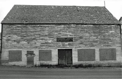 Side elevation of the Ryan Store and Fish Purchasing Centre, showing the clapboard walls that are outlined by finely proportioned trim, and by the slight eaves overhang and the narrow fascia, 1991. © Agence Parcs Canada / Parks Canada Agency, 1991.