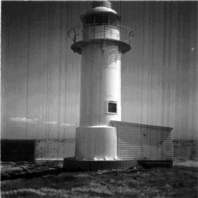 General view of the Channel Head Lighttower, showing the cylindrical massing of the tower consisting of several cylindrical segments and a small wood frame lean-to at its base, 1987. © Canadian Coast Guard/Garde côtière canadienne, 1987.