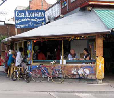 Photo of a cafe at the corner Baldwin Street and Augusta Avenue at the Kensington Market National Historic Site of Canada, 2004. © Agence Parcs Canada / Parks Canada Agency, Michel Pelletier, 2004.
