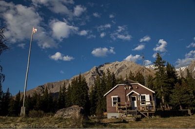 Windy Lodge Warden Cabin with mountain backdrop, 2018. © Agence Parcs Canada/ Parks Canada Agency, 2018.