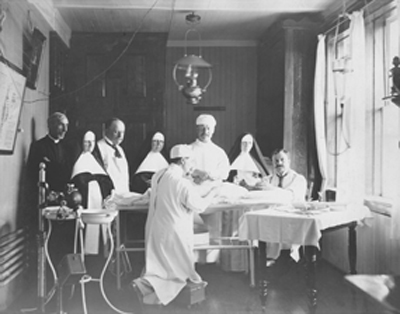 Title: Médecins spécialistes de l’Hôtel-Dieu de Montréal en visite à Saint-Basile, en 1906. 
Mère Maillet, la pharmacienne de la communauté, apparaît au centre de la photo. (© Parks Canada Agency / Agence Parcs Canada, Coll. des RHSJ de Saint-Basile, 2005.)
