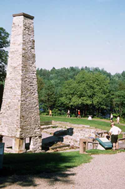 Vue de la cheminée et des vestiges de la forge basse au lieu historique national du Canada des Forges-du-Saint-Maurice, 2002. © Parks Canada Agency / Agence Parcs Canada, E. Kedl, 2002.