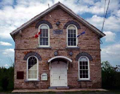 General view of Havelock Township Hall, showing its simple classical composition, as seen in its symmetrically placed windows on the front façade, its gable roof, regularly placed openings, and central entrance. (© Parks Canada Agency / Agence Parcs Canada.)