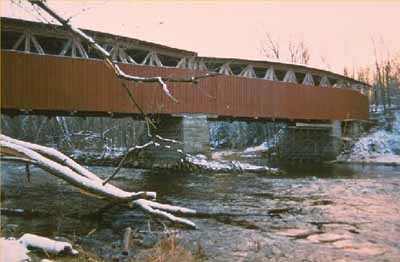 Vue de l'extérieur du pont couvert de Powerscourt, qui montre l'utilisation de planches et de lattes de parement verticales en bois. © Parks Canada Agency / Agence Parcs Canada.