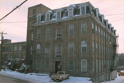 Exterior photo showing massing of 4 storey manufacturing building (© Parks Canada/Parcs Canada 1991)