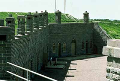 General view of the casemates bordering the Parade ground, 1982. © S. MacKenzie, Parks Canada Agency / Agence Parcs Canada, 1982.