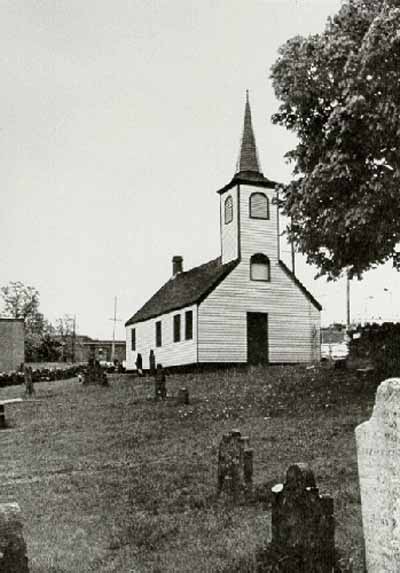 Vue de l'église Little Dutch, qui montre l’ensemble de stèles funéraires réparties au hasard sur le terrain en pente et accidenté, 1965. © Parks Canada Agency / Agence Parcs Canada, 1965.
