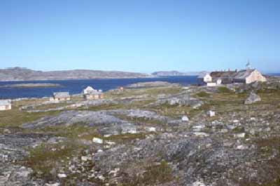 View of Hebron Mission in the distance, showing its isolated setting along the coast of Labrador, in proximity to the sea, 1994. © Parks Canada Agency / Agence Parcs Canada, I.K. MacNeil, 1994.