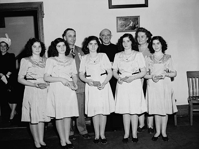 The Dionne quintuplets, accompanied by Mrs Olive Dionne and Frère Gustave Sauvé, take part in a program of religious music at Lansdowne Park, during the five day Marian Congress which prayed for peace and celebrated the centenary of the Ottawa archdiocese © National Film Board of Canada | Office national du film du Canada. Photothèque / Library and Archives Canada | Bibliothèque et Archives Canada / PA-155518