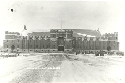General view of the Mewata Armoury, showing the rugged battlemented façade of stone and red sandstone distinguished by its central ogee-arched troop door, 1918. © Public Works Dept. | Ministère des travaux publics / Library and Archives Canada | Bibliothèque et Archives Canada / PA-053020