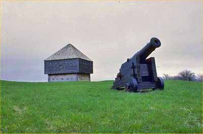 Vue en angle montrant deux façades du fort Edward son emplacement en relation avec les autres éléments paysagers du fort tel que le canon, 1991. © Parks Canada Agency/ Agence Parcs Canada, 1991.