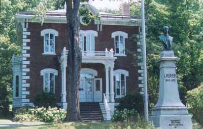 Vue de la façade du lieu historique national du Canada de la Maison-Wilfrid-Laurier, qui montre un buste de Laurier, 1999. © Agence Parcs Canada / Parks Canada Agency, N. Clerk, 1999.