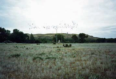 View of the 1946 Fort Whoop-Up cairn, placed by the Lethbridge Chamber of Commerce at the location of the archaeological remains of Fort Whoop-Up. (© Trudy Cowan, Parks Canada | Parcs Canada, 1989.)