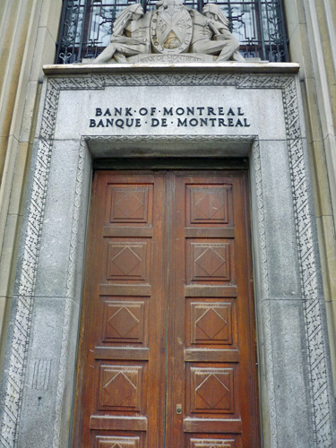 General view of the Bank of Montreal, showing its central doorways with a carved moulding and a superimposed sculpture of the bank’s coat of arms above, 2011. © Parks Canada Agency / Agence Parcs Canada, M. Therrien, 2011.