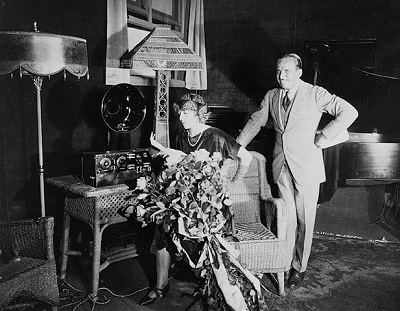 Douglas Fairbanks et Mary Pickford, au studio de CKAC (le microphone est sous l'abat-jour) (© Bibliothèque et Archives Canada | Library and Archives Canada / PA-139111)
