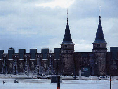 The symmetrically organized entry facade with central arched doorway flanked by pinnacled circular towers facing the parade square. © Parks Canada | Parcs Canada