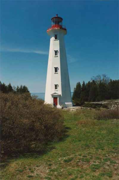 General view of the Light station Tower, showing its simple massing, consisting of a slim octagonal structure with prominent lantern, and the four levels of six-paned windows, 1990. (© Department of Transport / Ministère des Transports, 1990.)