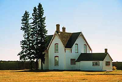 General view of the Commanding Officer’s Residence, emphasizing its Eastern Canadian standard in residential design, namely its two storeys, gable roof and L-shaped plan, 2002. © Parks Canada | Parcs Canada, T. Verishine, 2002.