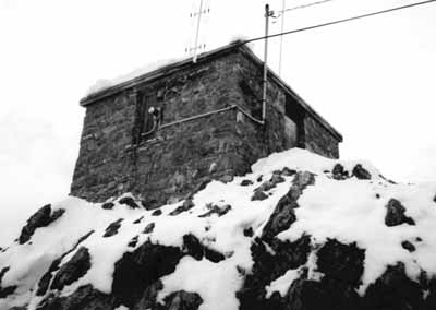 Side view of Sulphur Mountain Weather Station, showing its simple, one-storey massing with a hipped roof, 1986. (© Environment Canada, Parks Canada, Western Regional Office, 1986 / Environnement Canada, Parcs Canada, Bureau de la région de l'Ouest, 1986.)