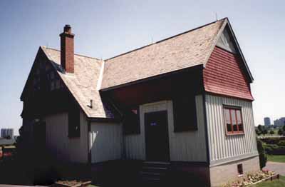 Vue de l'entrée de l'atelier de rempotage, qui montre le bardage de planches et tasseaux et le faux-colombage des pignons d’extrémité, 1995. © Parks Canada Agency / Agence Parcs Canada, 1995.