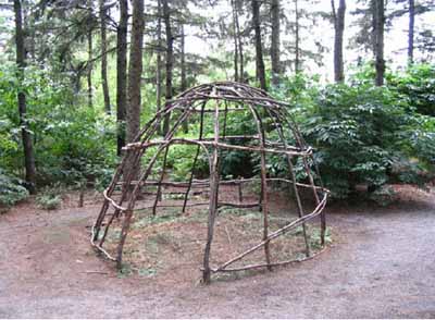 A tent-like creation made out of wood in a forest