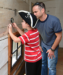 Man and child looking at images left on the walls of the Fort Edward blockhouse.