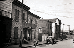 photography showing children playing in the street in front of a row of wooden houses