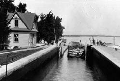 A Barge entering lock number 3 of the Chambly Canal. To the left, a lockhouse built in Neo-Queen-Anne style.