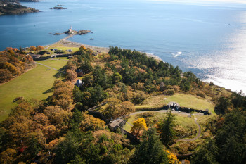 Aerial view of fort walls with a lighthouse beyond.