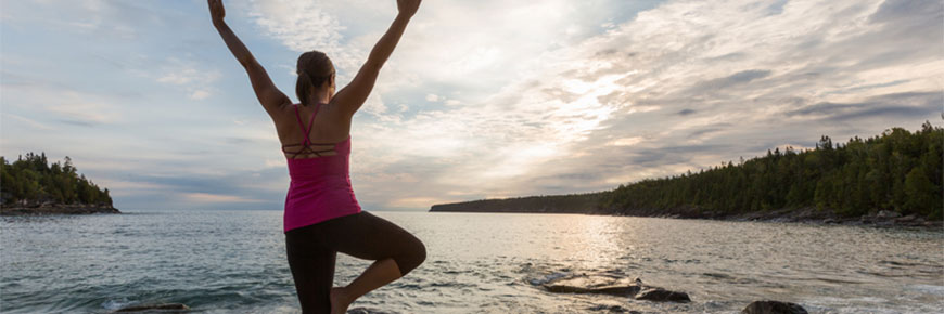 A woman does yoga on a beach at sunrise.