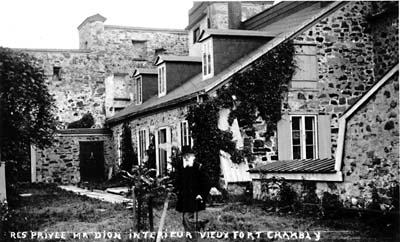 Monsieur Joseph-Octave Dion est photographié devant sa maison construite à même les murs du fort