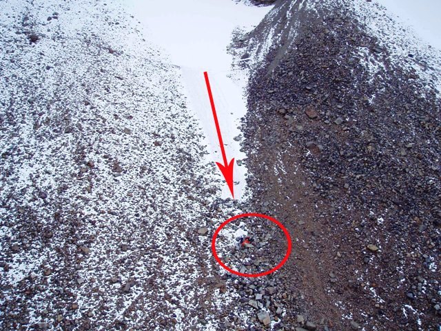 Le lieu de l’accident. La flèche montre la pente enneigée sur laquelle le randonneur a glissé. Le cercle montre la zone de dépôt rocheuse où il a atterri après sa glissade effrénée.