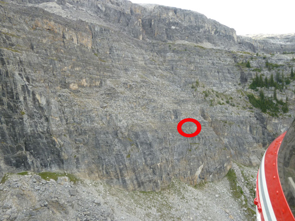 Le grimpeur en détresse est visible dans le cercle en rouge. Cette photo a été prise de l'hélicoptère pendant que les spécialistes survolaient le secteur. Observez le terrain extrêmement escarpé en amont et en aval. 