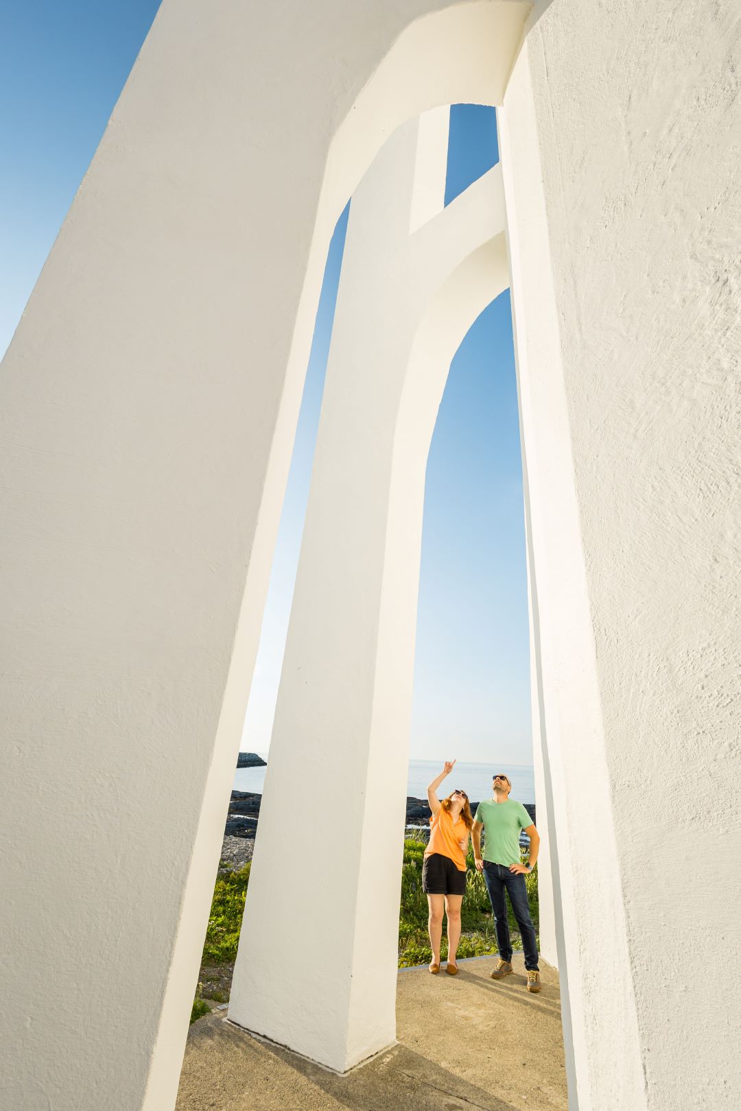 A couple examine the concrete hoops near the lighthouse.
