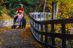 A visitor in a wheelchair is guided along the Freshwater Lake trail