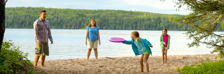 A family of 4 play Frisbee at the beach. 
