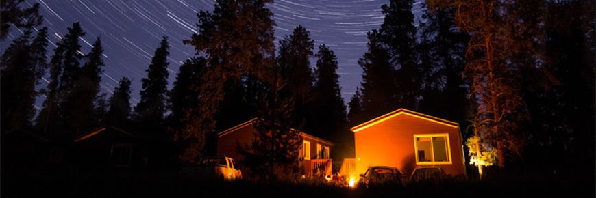 Two cabins lie underneath a starry night sky.